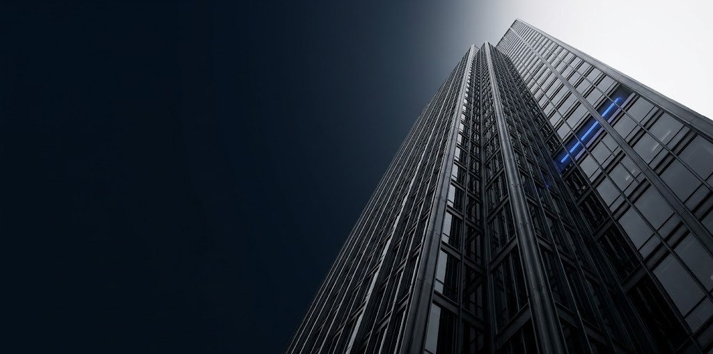 A modern glass-and-steel corporate tower rising against a clean sky